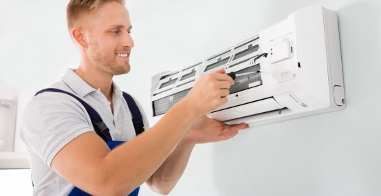 Happy Male Technician Repairing Air Conditioner — Electricians in Warana QLD