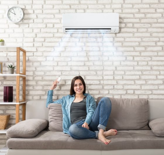 Happy Young Woman Holding Remote Control — Air Conditioning in Maroochydore QLD