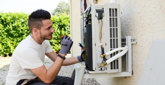 Electrician Fixing A Compressor Of An Air Conditioning Unit