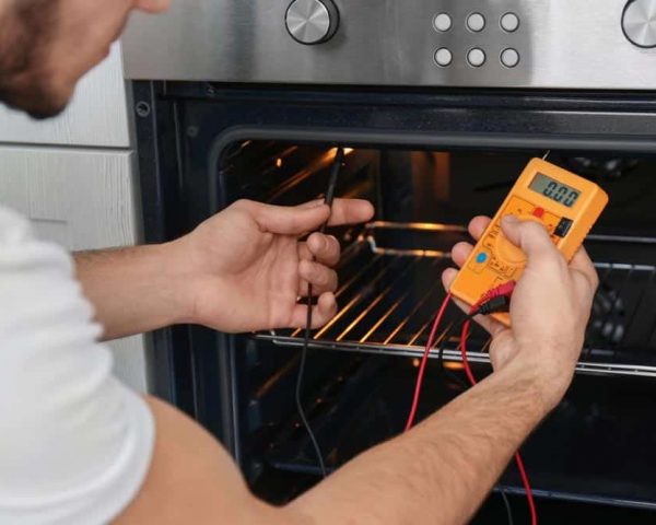 Electrician Using Multimeter On An Oven